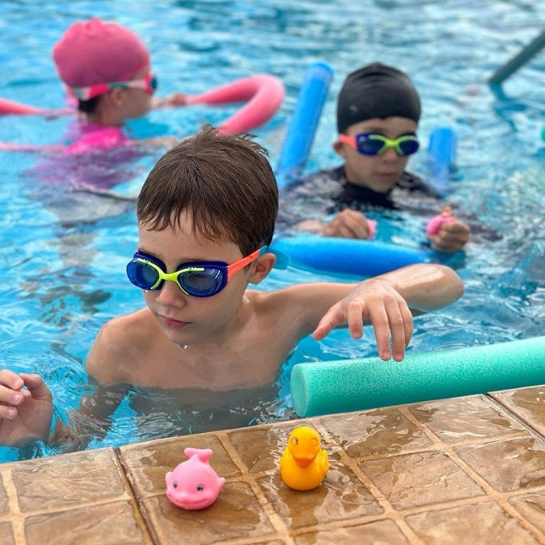 Alunos de natação pegando brinquedos e organizando os mesmos