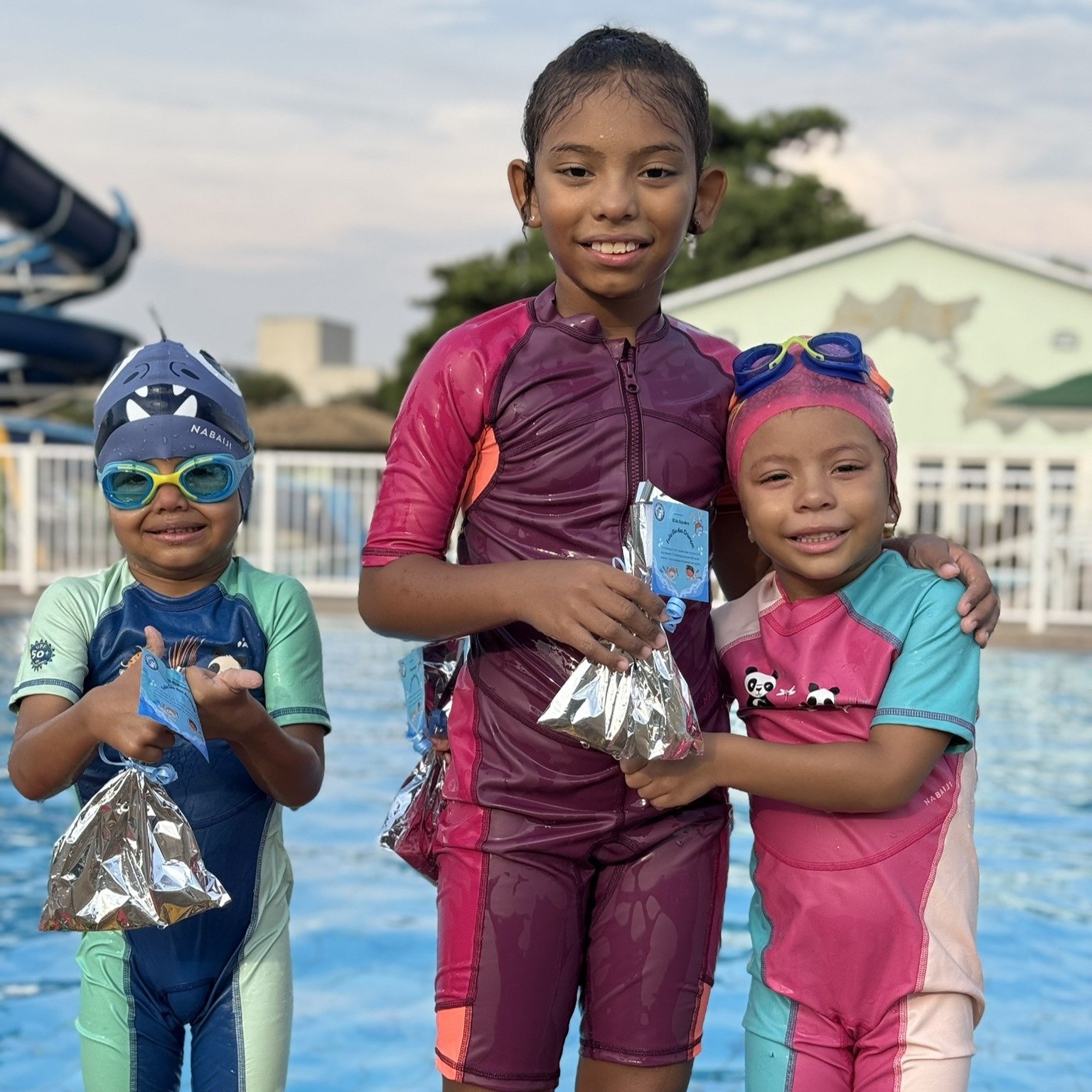 3 alunos de natação fazendo pose para foto mostrando a lembrancinha que ganharam no dia das crianças